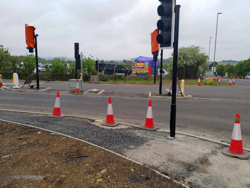 A photo of the traffic lights where the proposed Bishop's Cleeve Cycle route will cross. A narrow pavement and a gap in kerbing is visible, but no lights are installed as yet.